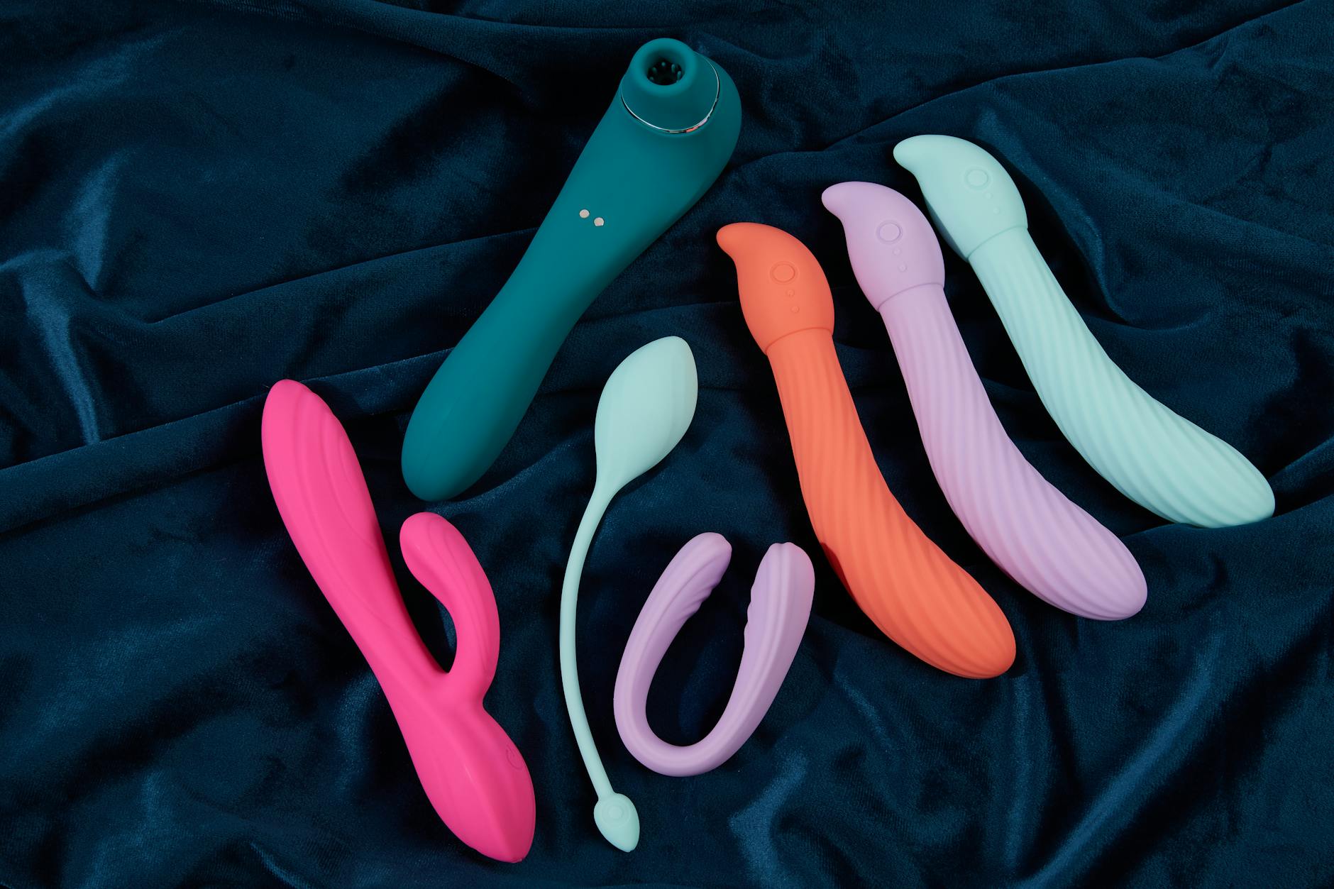 Collection of compact silicone vibrators in various colors arranged on dark fabric