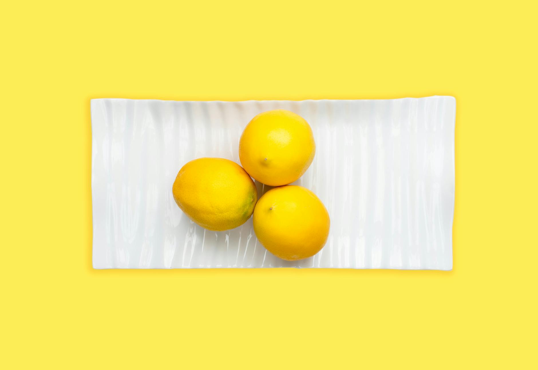 Fresh lemons arranged on a white plate with vibrant yellow background, symbolizing renewal and sensitivity shifts
