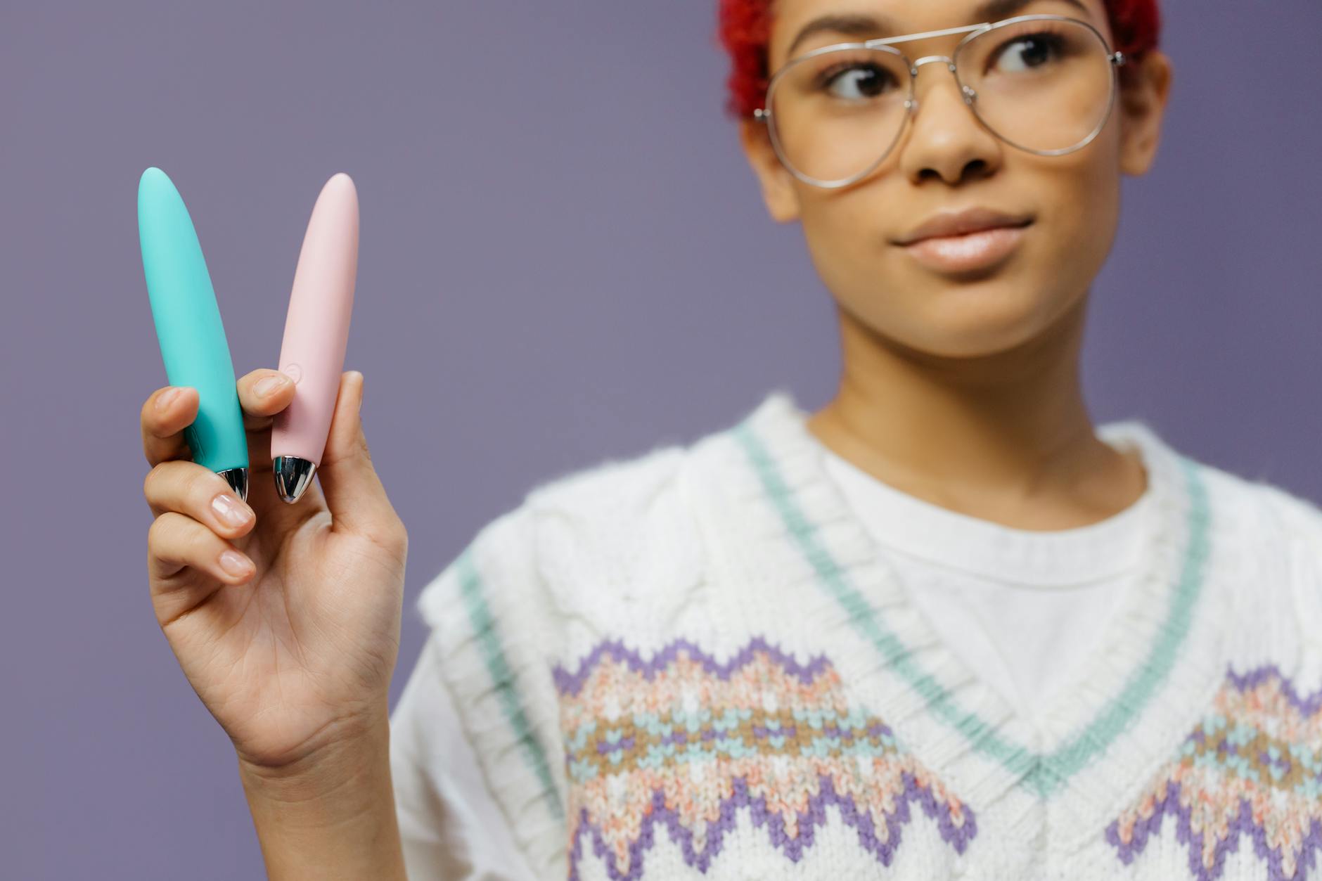 Two colorful vibrators held against a purple background, representing different stimulation styles.