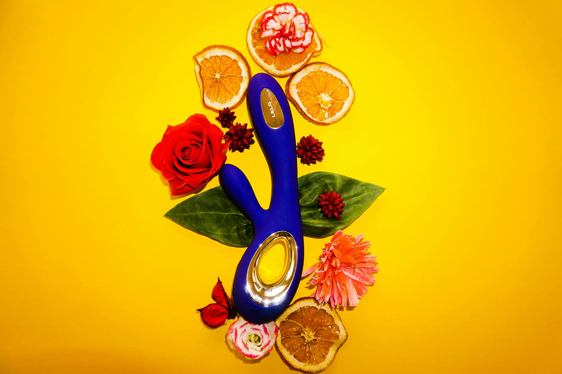 Lemon Vibrator umgeben von Blüten und Zitronenscheiben auf gelbem Untergrund