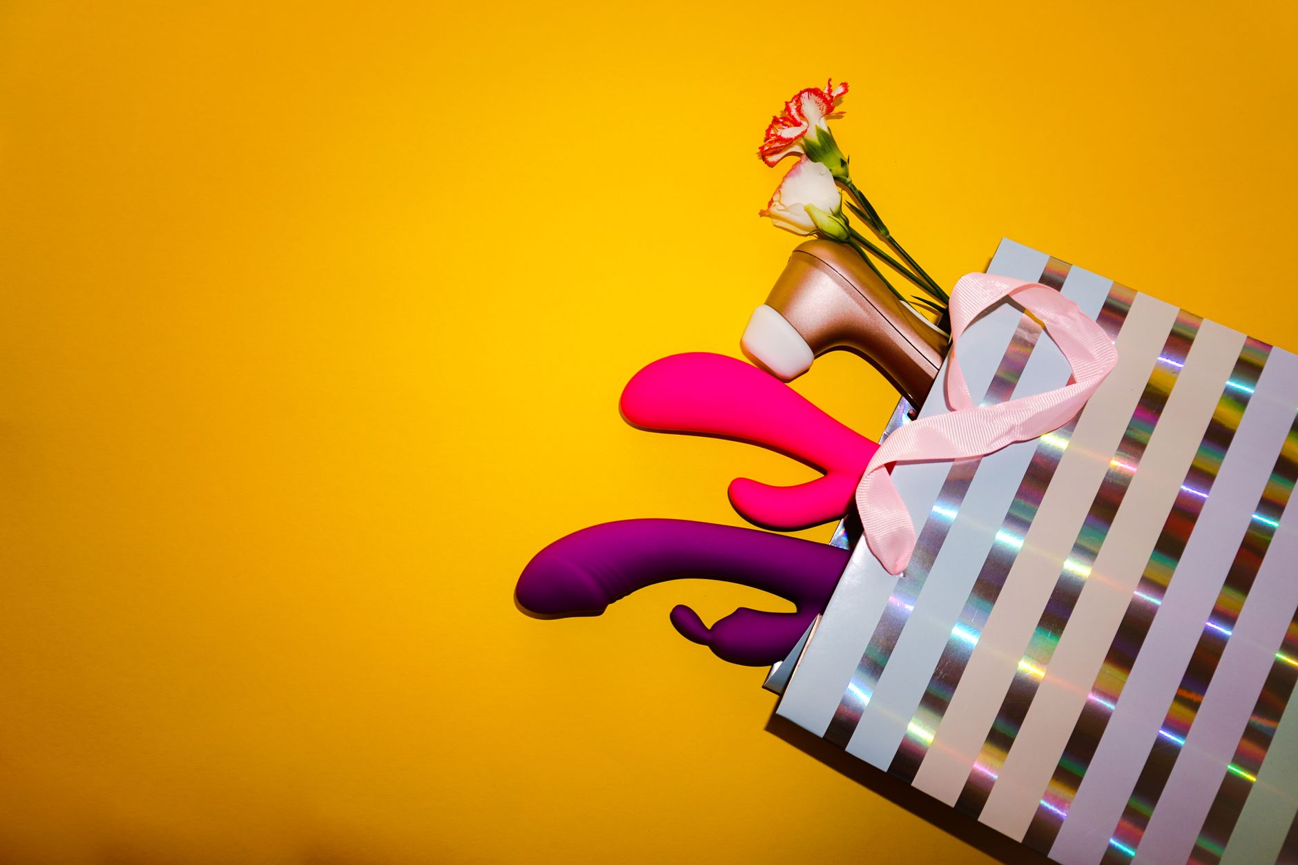 Colorful vibrators with flowers in a holistic gift arrangement, symbolizing inclusive pleasure for all bodies.