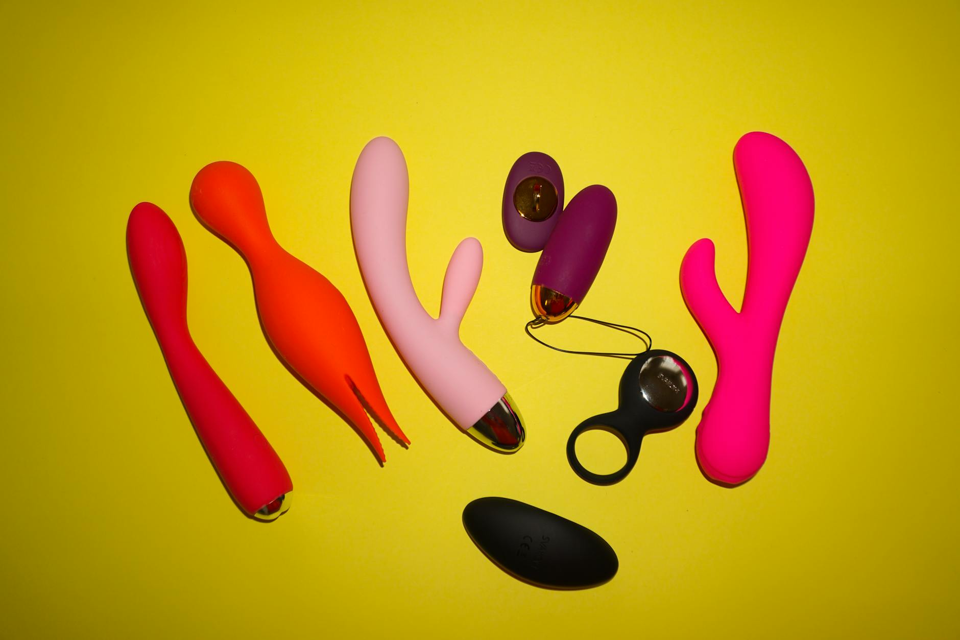 Colorful clitoral vibrators arranged on a bright yellow background, showcasing different options for cycle-aware pleasure