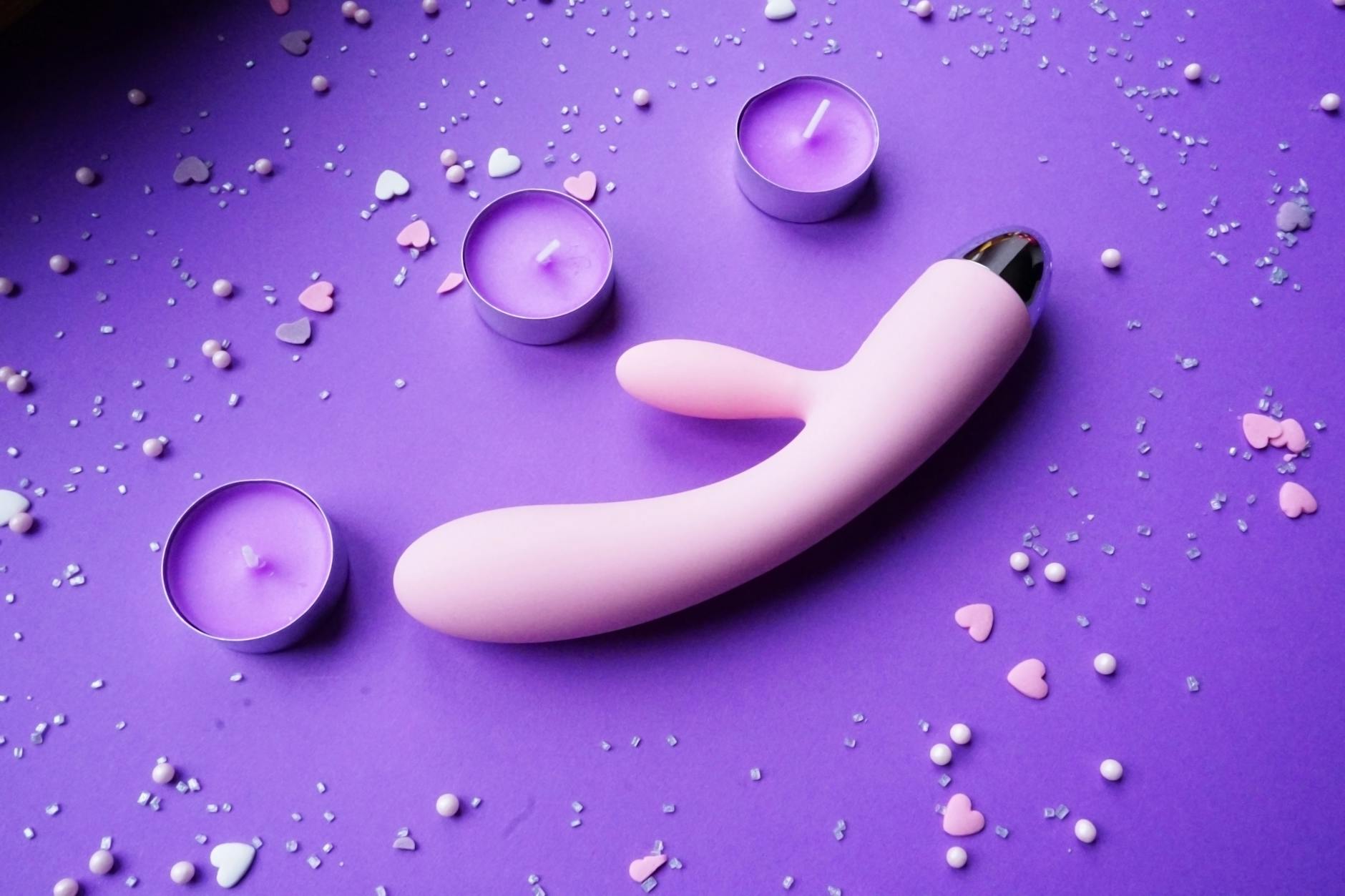 A teal lemon clitoral vibrator resting on smooth white silk fabric